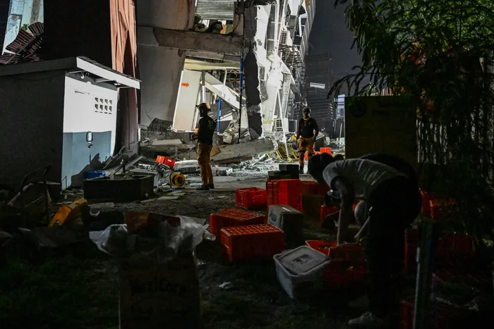 Recovery crews working at night beside a collapsed building after the earthquake.